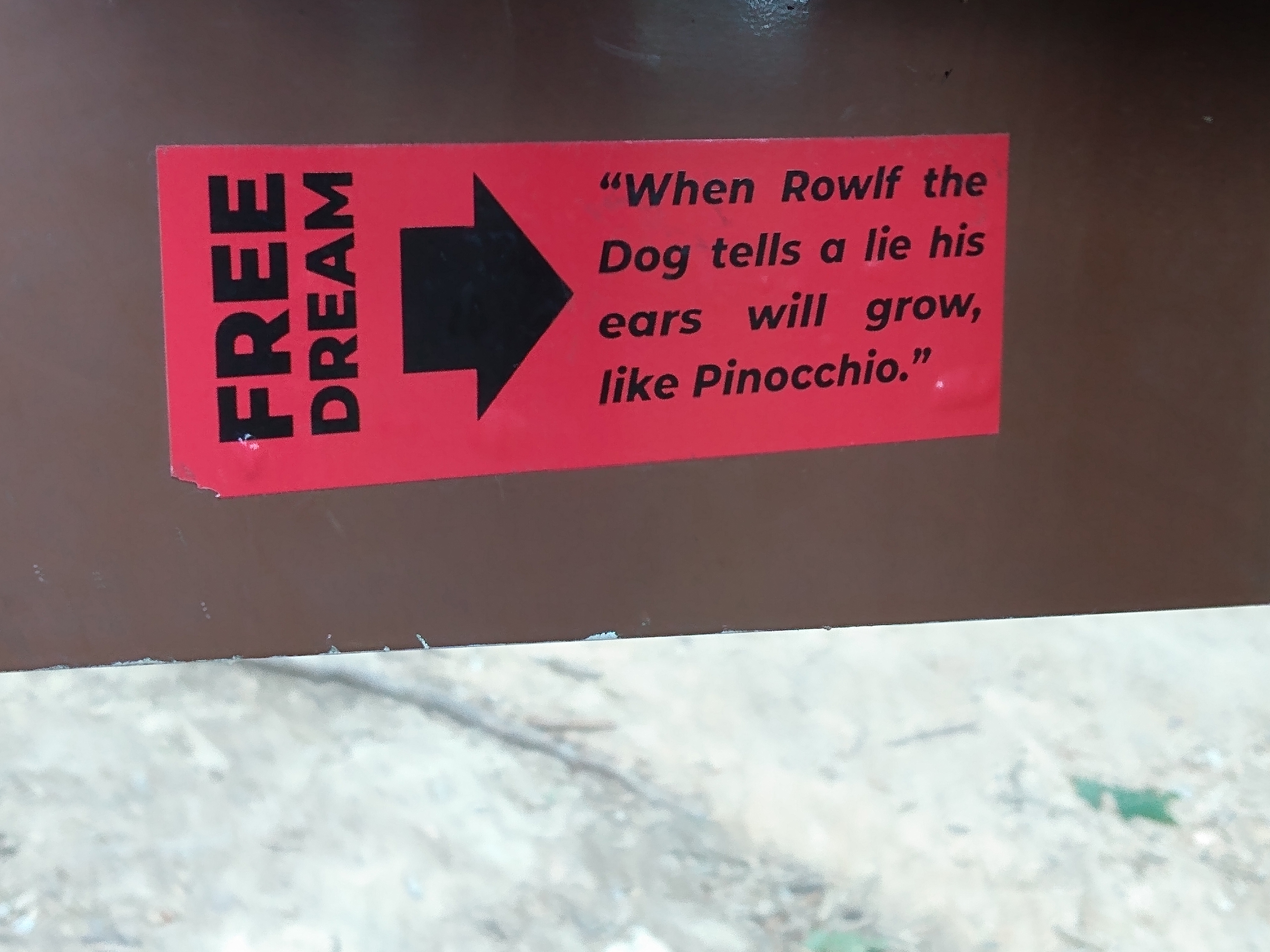 A sign with a sticker saying "Free Dream. When Rowlf the Dog tells a lie his ears will grow, like Pinocchio."